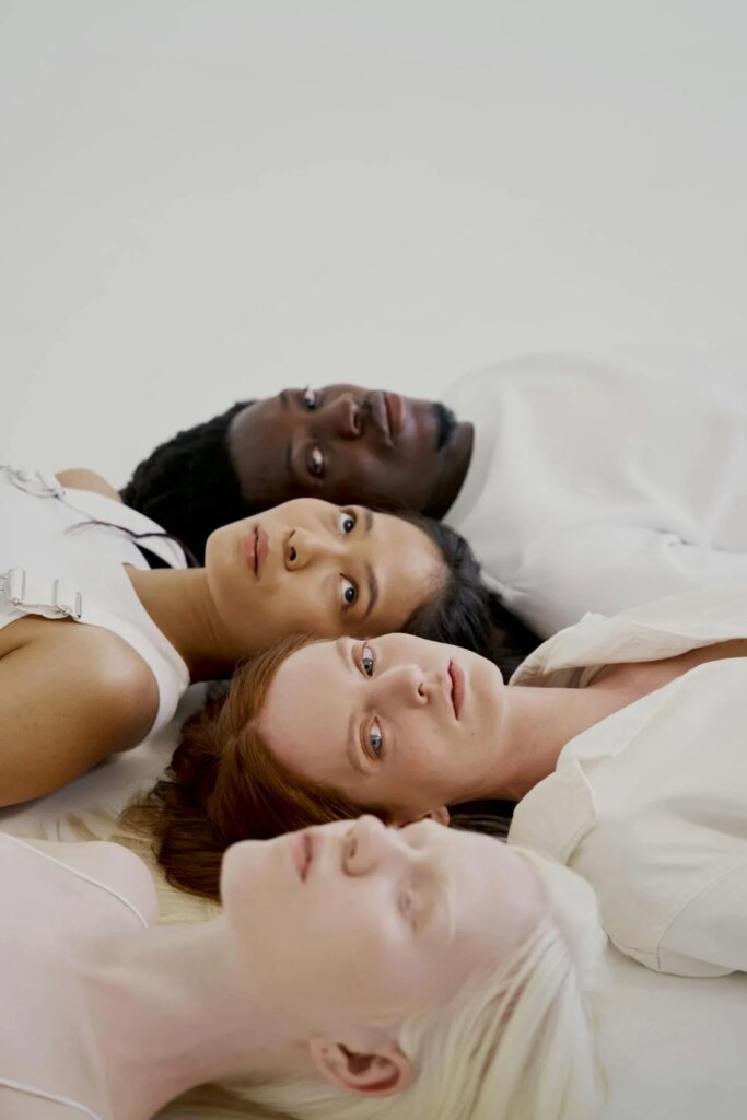 Women and man lying on white surface